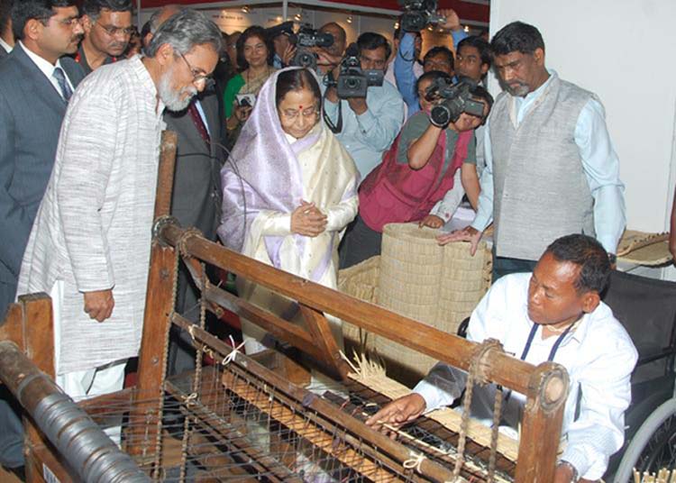 President Pratibha Devisingh Patil watching physically challenged innovator, Y. Mangi Singh from Kakching weave the Kouna Mat on his indegenously developed machine at the exhibition.